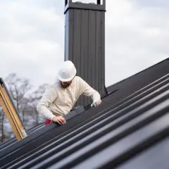 Pracownik na dachu montuje blachę, dbając o szczelność dachu, czy to będzie blacha z filcem czy membrana, ważne by było solidnie.