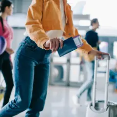 Widok na odprawę na lotnisku: kobiety z bagażami i paszportami, gotowe do podróży.