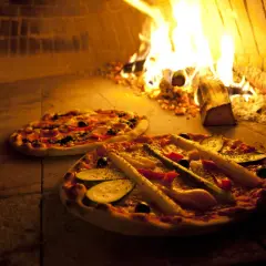 Zwei Pizzen im Holzofen, die Hitze des Feuers sorgt für die perfekte pizza ofen temperatur.
