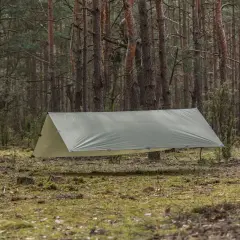 Rozstawiony tarp w lesie, pokazujący, jak zabezpieczyć namiot przed deszczem. Zapewnia schronienie przed wilgocią.