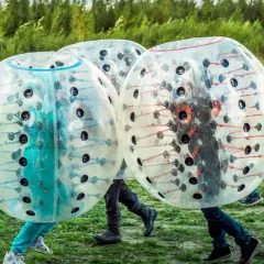 Tre personer i genomskinliga bubblor, redo för bumperball hyra. En rolig utomhusaktivitet med mycket skratt.