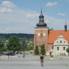 Włocławek atrakcje na weekend: plac z katedrą, spacerowicze, drzewa i zielone wzgórza w tle.