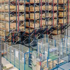 Wysoki regał magazynowy z paletami i wózek widłowy w nowoczesnym centrum logistycznym.