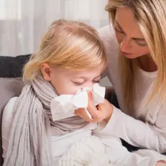 Mama troszczy się o dziecko z zielonym katarem, podając mu chusteczkę.