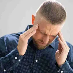 Uomo con le mani sulle tempie, sofferente, cerca sollievo per come eliminare le vertigini.