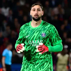 Gianluigi Donnarumma, bramkarz PSG, w zielonej koszulce i czerwonych rękawicach, gotowy do obrony.