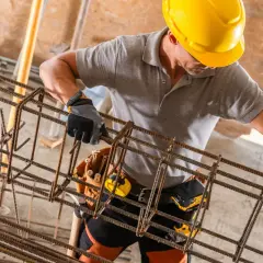 Kontraktor kto to? Pracownik budowlany w żółtym kasku i rękawicach pracuje przy zbrojeniu.