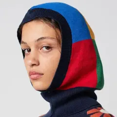 Mujer con balaclava que es una prenda de punto multicolor, con bloques de azul, rojo, amarillo y verde.