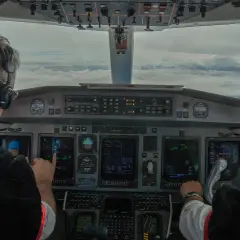 Dwóch pilotów w kokpicie, jeden wskazuje na ekran. Zastanawiasz się, ile zarabia pilot? To praca pełna odpowiedzialności.