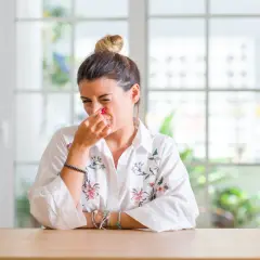Femme pince son nez, visiblement incommodée par des nuisances olfactives. Elle prépare peut-être une lettre au maire.