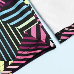 Close-up of colorful geometric leggings. The fabric is black with vibrant stripes of pink, blue, yellow, and green. The stitching shows how you can sew leggings.