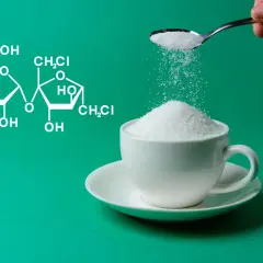 Struktura chemiczna sukralozy obok filiżanki białego cukru. Czy wiesz, sukraloza co to jest?