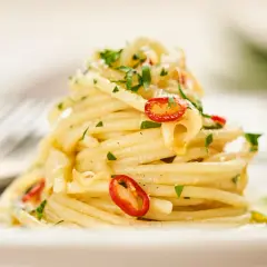 Ein Berg von Spaghetti Aglio e Olio, garniert mit frischer Petersilie und scharfen Chilischeiben.