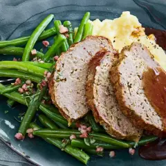 Saftiger hackbraten im ofen, serviert mit grünen Bohnen und Kartoffelpüree, übergossen mit dunkler Soße.