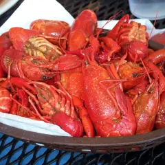 En korg full med saftiga kräftor, redo för en härlig seafood boil. En liten skål med röd sås står bredvid.