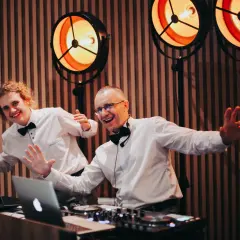 Dwóch DJ-ów w białych koszulach i czarnych muszkach, gotowych do zabawy. Zastanawiasz się, ile kosztuje dj na wesele?