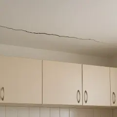 Długie pęknięcie na suficie nad szafkami kuchennymi. To może być dowód na odpowiedzialność dewelopera za pęknięcia ścian.