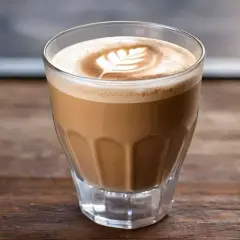 Ein Glas mit cremigem Espresso mit Milch, spanisch. Latte Art Blattmuster auf dem Milchschaum.