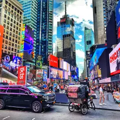 Times Square w Nowym Jorku z neonami, ludźmi i rikszami.