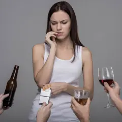 Kobieta w białej koszulce zastanawia się, jak przestać pić alkohol wieczorami, gdy wokół niej pojawiają się różne używki.