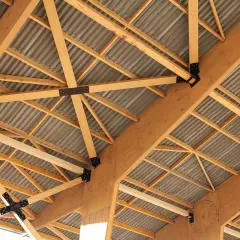 Structure complexe de poutres en bois de type **lvl bois**, soutenant un toit ondulé.