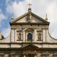 Majestatyczna fasada kościoła, przykład bogatej architektury baroku, z rzeźbami i zdobieniami.