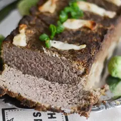 Pyszny pasztet drobiowo-wieprzowy z wątróbką, udekorowany zieloną cebulką i podany z brukselką.