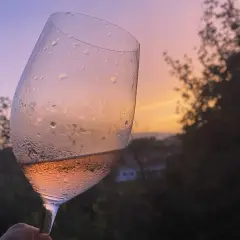 Calice di vino rosato, con gocce di condensa, al tramonto. Un brindisi alla vinificazione in rosato.
