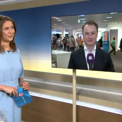 Moderatorin hält Umschlag mit Logo von tv-n hessen. Auf dem Bildschirm ein Reporter im Anzug.