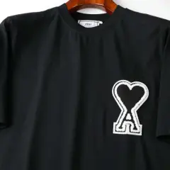 Czarna koszulka z logo serca i literą "A" od firmy AMI Paris.