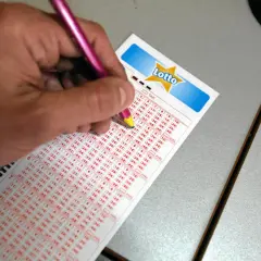 Ręka z różowym ołówkiem zaznacza liczby na kuponie Lotto, być może to właśnie tutaj padną wygrane.