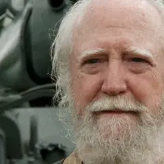 Hershel Greene, członek obsady "Żywych trupów", z siwą brodą i włosami, na tle pojazdu.