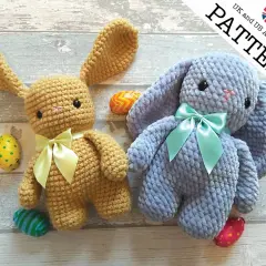 Due coniglietti amigurumi, uno color miele e uno azzurro, con fiocchi e uova di Pasqua.