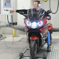 Mechanik sprawdza motocykl na hamowni. Regularny przegląd motocykla 125 zapewni jego sprawność.