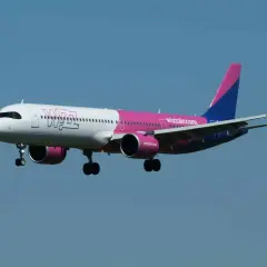 Samolot Wizz Air z różowym i niebieskim ogonem zbliża się do lądowania. W bagażniku rejestrowanym Wizzair zmieści się wszystko, czego potrzebujesz.