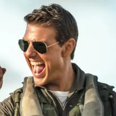 Tom Cruise w okularach przeciwsłonecznych i kurtce pilota, z zaciśniętą pięścią, krzyczy z radości. Czekamy na **Top Gun 3**!