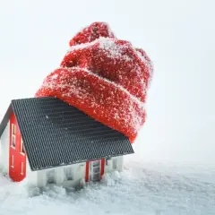 Mały domek w śniegu, przykryty czerwoną czapką, symbolizuje okres ochronny przed eksmisją.