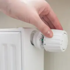 Mano ajustando el termostato de un radiador para decidir a que temperatura poner los radiadores y ahorrar energía.
