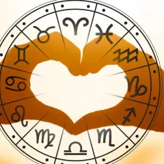 Dłonie tworzą serce na tle koła zodiaku, gdzie uran w koziorożcu symbolizuje przełom w dążeniu do celu.
