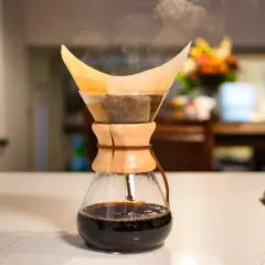 Dampf steigt auf bei der Chemex Zubereitung. Frisch gebrühter Kaffee tropft in die Glaskaraffe.