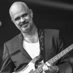 Jacek Budyń Szymkiewicz, w garniturze i z gitarą Fender Stratocaster, gra na scenie.