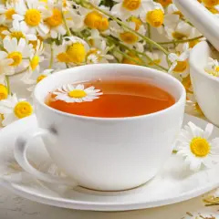 Aromatyczne picie rumianku w filiżance, obok świeżych kwiatów i moździerza z suszem.