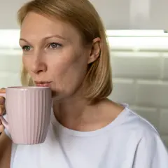 Kobieta pije kawę z różowego kubka. Zastanawia się, czy 200 mg kofeiny to dużo.