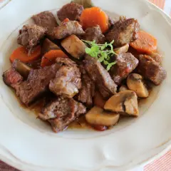 Pyszne wołowina po burgundzku z marchewką i grzybami na talerzu. Aromatyczne danie, które zachwyca smakiem.