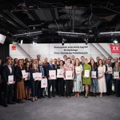 Grupa nagrodzonych osób z dyplomami na tle sceny z logo XX Rankingu Firm i Doradców Podatkowych.