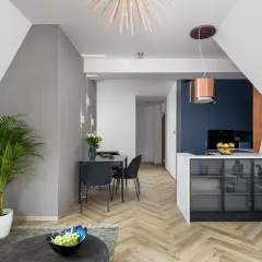 Nowoczesna kuchnia z granatowymi frontami i miedzianym okapem. W salonie elegancka jadalnia i duża palma. Domowe rewolucje w stylowym wydaniu.