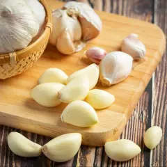 Ząbki czosnku, świeżo obrane, leżą obok całych główek. Ten aromatyczny chiński czosnek jest gotowy do dodania smaku potrawom.
