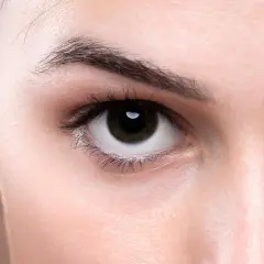 Zbliżenie na oko z ciemną tęczówką, gdzie widoczna jest bogata w **melaninę** skóra i rzęsy.