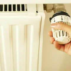 Dłoń reguluje termostat grzejnika. Czy piec gazowy powinien chodzić cały czas? Ustawienie 5 oznacza 20°C.