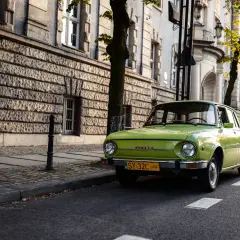 Zielona Skoda 105/120 na tle zabytkowej kamienicy. Ile lat musi mieć budynek żeby był zabytkiem? Ten ma ponad 100 lat.